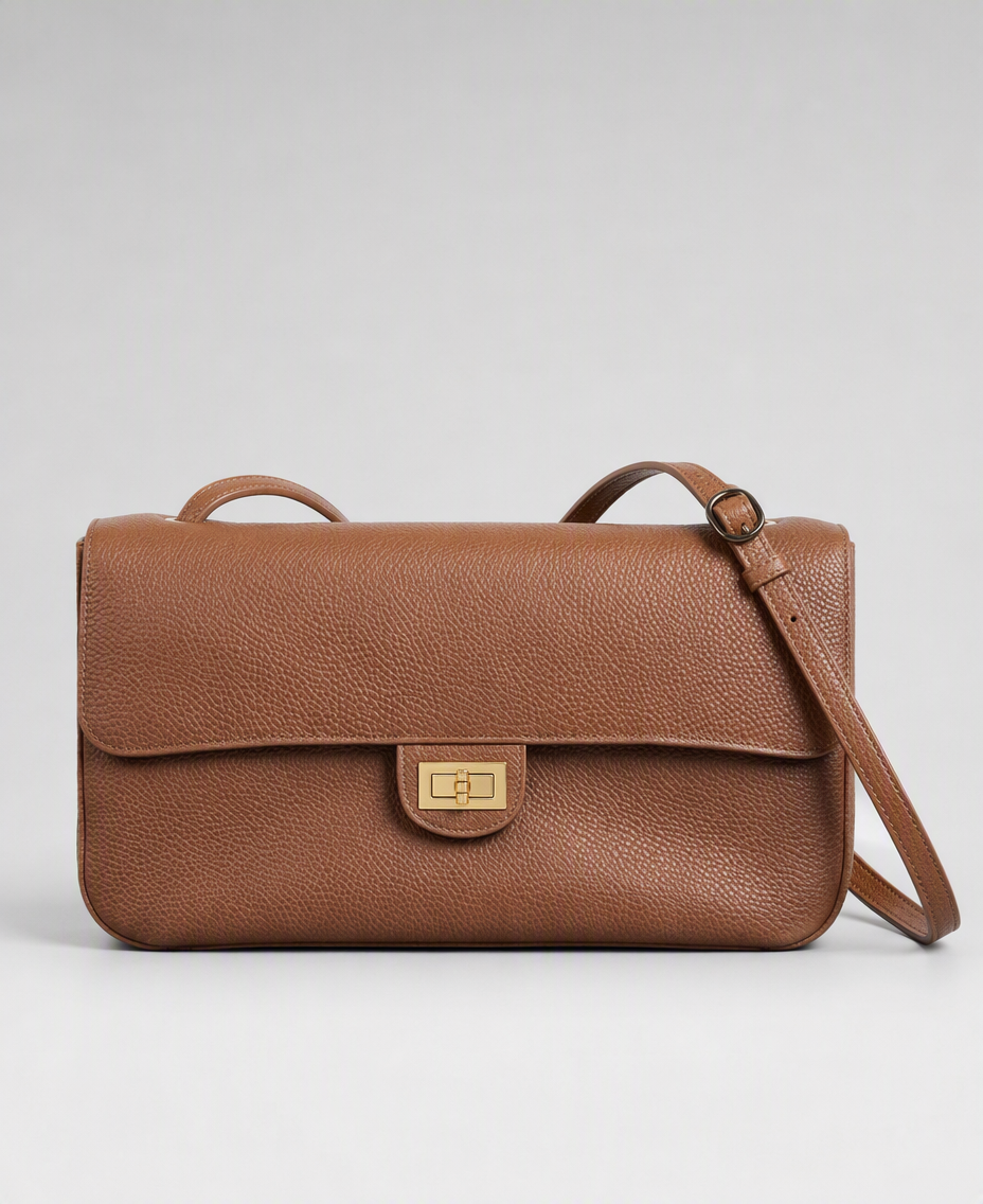 AI-generated product photograph for Hope Roza: the tan pebbled-leather Trove 26 shoulder bag with a gold turn-lock clasp and adjustable strap on a plain grey studio background